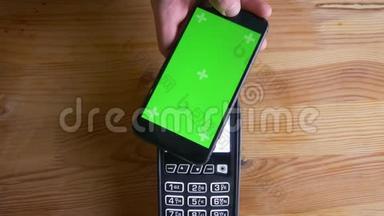 一款支付终端的特写镜头，用于手机上的应用程序支付，室内有绿色屏幕